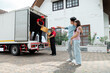 © Rakchanok - Happy couple using professional moving house services company deliver to new house, team of mover workers carry boxes, man and woman waiting uploading furnitures and boxes, shipping men at work