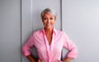 A mature woman with elegant grey hair, clad in a pink shirt, symbolizes the resilient spirit in the battle for breast cancer awareness and women's health.