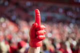 Fototapeta  -  A spectator enthusiastically waving a foam finger at a sports event, exemplifying the high energy and spirit of the game