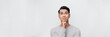 © makistock - Smart handsome smiling young Asian man thinking with hand on chin on white background. Banner