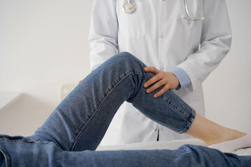 Wall Mural - Doctor and patient are at the usual medical inspection in the clinic. Therapist examines a young woman's knee. Medicine concept