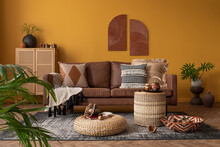 Warm And Cozy Composition Of African Living Room Interior With Mock Up Poster Frame, Brown Sofa, Pouf, Rattan Sideboard, Vase With Leaves, Pillows And Personal Accessories. Home Decor. Template.