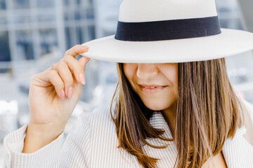 Portrait of a cheerful smiling woman wearing a stylish hat and glasses outdoors close up.