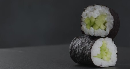 Sticker - Maki rolls with cucumber on a dark background. Close-up footage on the rotating table.