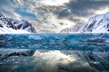 Wall Mural - mirror reflection of the blue glacial ice, mountains and clouds of kongsvegen glacier, in kongsfjord