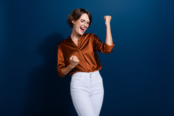 Sticker - Photo of overjoyed cheerful girl dressed stylish clothes celebrate success raise hands fists isolated on dark blue color background