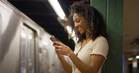 Poster - Young black woman using smartphone at a subway platform