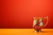 Kikombe cha Umoja Unity Cup for Kwanza, gilded with geometric patterns on an orange surface against a warm red background