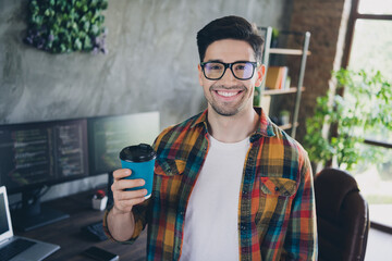 Photo of cheerful intelligent web developer toothy smile hand hold fresh aroma coffee cup loft office indoors
