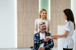 © Iryna - Disabled elderly man in wheel chair being registered at the hospital by his companion.
