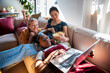 © Marko Geber - Group of three young diverse female friends watching a movie on the laptop at home