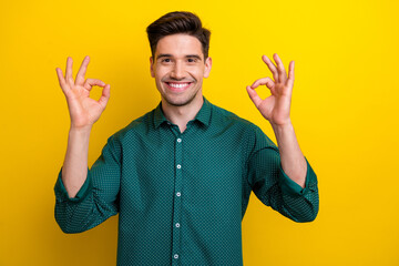 Wall Mural - Photo of cool cheerful man wear green trendy clothes demonstrate thumbs up recommend quality product isolated on yellow color background