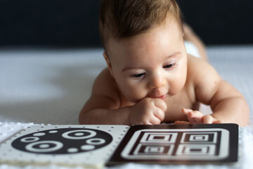 a baby looks at a black and white contrast educational book. intellectual development of newborns. d