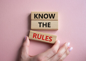 Sticker - Know the rules symbol. Wooden blocks with words Know the rules. Beautiful pink background. Businessman hand. Business and Know the rules concept. Copy space.