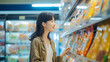 © Pillow Productions - A young Chinese woman browses products while shopping in a grocery store.