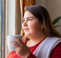 Sticker - Woman having a cup of coffee looking through a window