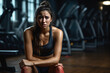 Woman in gym versing emotional upheaval amid sweat weights and mirrors 