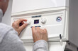 © Brian Jackson - Adjusting thermostat setting on home heating system central heating boiler