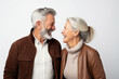 Happy couple in their 60s, smiling, looking at each other, white background