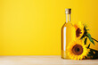 A bottle of sunflower oil and sunflower on yellow background.