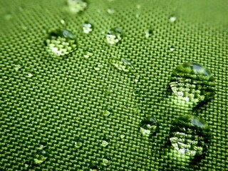 Close-up shot of a green cloth, with water droplets reflecting the light