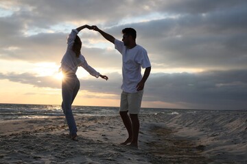 Poster - Happy couple dancing on beach at sunset