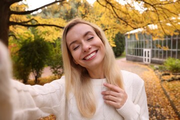 Sticker - Portrait of happy woman taking selfie in autumn park