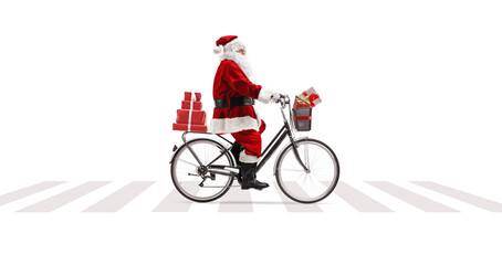 Poster - Full length profile shot of Santa Claus riding a bicycle at a pedesrian crossing and carrying presents