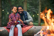 Happy black father and daughter enjoy by bonfire while camping in woods.