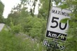 Maximum 50 km an hour sign with overgrown plants in Ontario, Canada.
