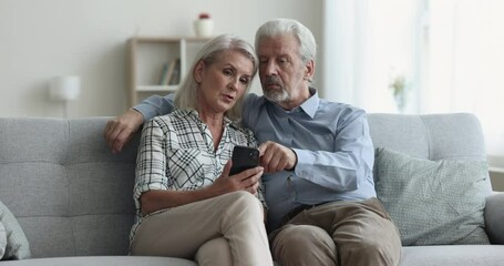 Canvas Print - Caring senior husband teaching mature wife to use new online app, financial service on mobile phone, making order on Internet, using modern Internet technology, wireless communication