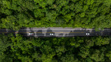 Fototapeta Uliczki - Aerial view asphalt road in the middle fores with car, Asphalt road through the mountain and green forest.
