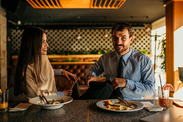 Wall Mural - A diverse business pair, a man and a woman, at a restaurant, deciding what to order for lunch