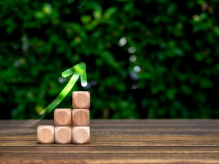 Poster - Rise up glowing arrow on empty wooden cube blocks as a business chart steps on table and green leaves background with copy space. Business growth, investment, sustainable development goals concepts.