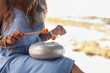 Close up of woman hands play relaxing melody on hapi steel tongue drum on seaside. Perfect lady playing relax music at tropical beach. Tropic summer vacation, meditating concept. Copy ad text space