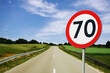 Speed limit sign with trees behind. Maximum seventy kilometers per hour. Safety on road background. White round sign red border line. Traffic ticket background. Speeding fine.