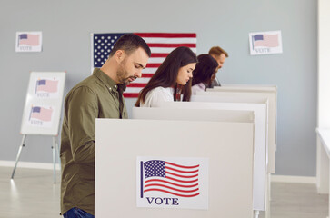 Wall Mural - Vote. Young responsible people think and vote while standing in voting booths at polling station. Side view of Americans voting on election day. Concept of elections in United States of America.