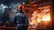 Blue-collar worker wearing protective helmet looking at burning furnace in industry.
