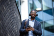 © littlewolf1989 - Happy man in business suit listening to music on headphones and going to work. In background modern buildings.