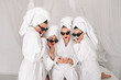 Well-groomed girls get together to celebrate a bachelorette party. Women after spa treatments, wrapping their heads in a towel, enjoy the fun. Concept of entertainment and spa treatments for women.