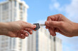 © Roman - hands of people handing each other the key to a new apartment on the background of a new building. selective focus.