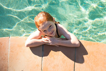 Young Girl Looking Up From The Side Of A Swimming Pool