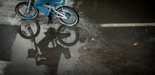 A Cyclist Riding Around A Puddle On The Road.