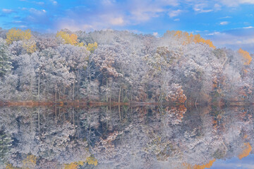 Wall Mural - Autumn landscape at sunrise of the shoreline of Long Lake flocked with snow and with mirrored reflections in calm water, Yankee Springs State Park, Michigan, USA