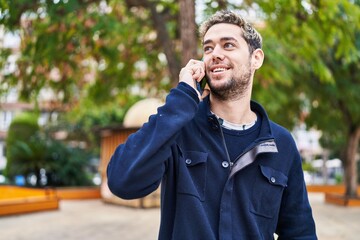 Young man smiling confident talking on the smartphone at park