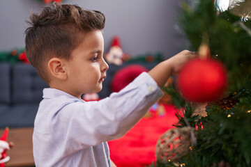 Adorable hispanic toddler decorating christmas tree at home