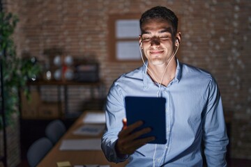 Sticker - Handsome hispanic man working at the office at night smiling looking to the side and staring away thinking.