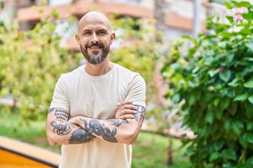 Wall Mural - Young bald man standing with arms crossed gesture at park