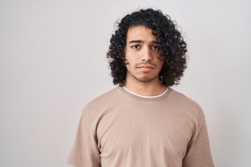 Wall Mural - Hispanic man with curly hair standing over white background depressed and worry for distress, crying angry and afraid. sad expression.