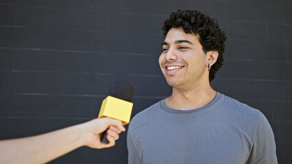 Sticker - Young latin man having interview smiling over isolated black background